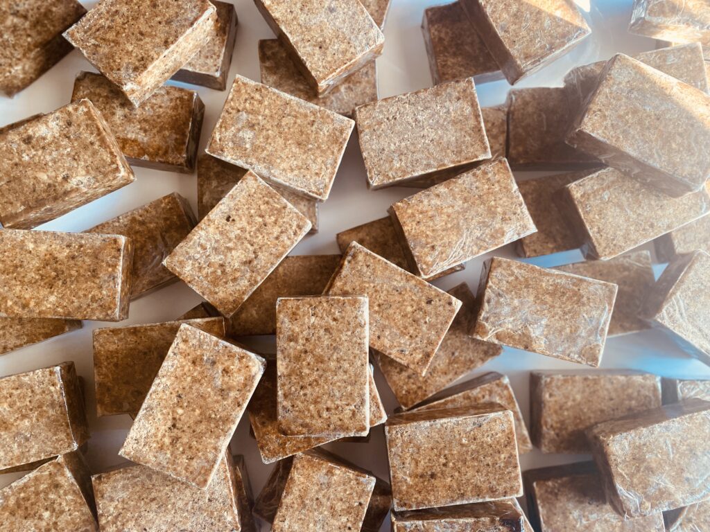 A close-up of unrefined African Black Soap chunks with natural texture.