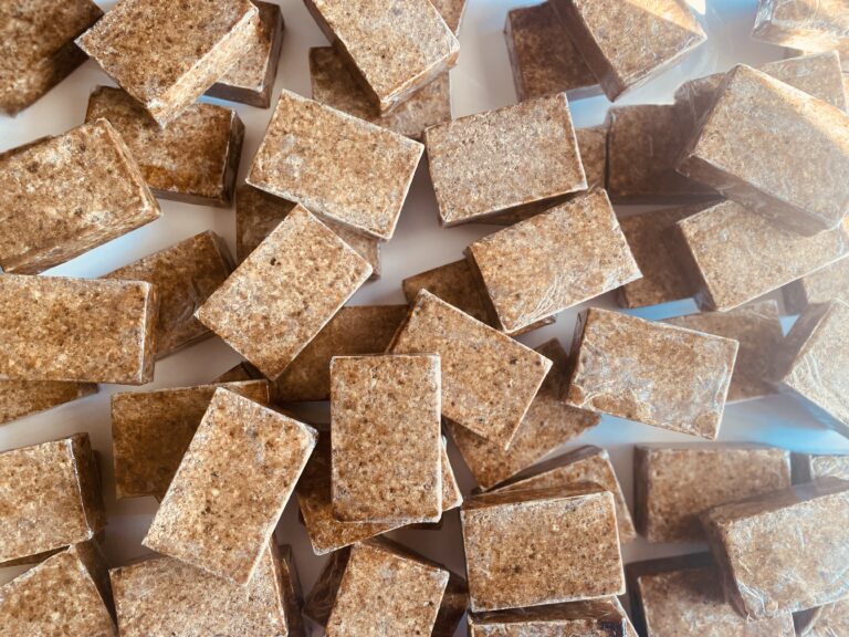 A close-up of unrefined African Black Soap chunks with natural texture.